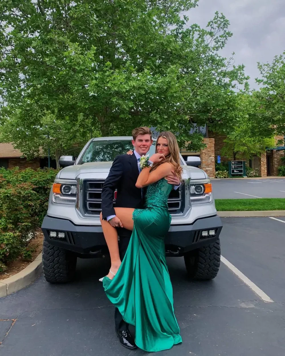 Сouple wearing a green gown and a black suit near the car