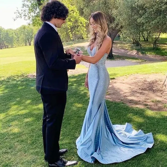 Сouple wearing a blue gown and a black suit on the grass